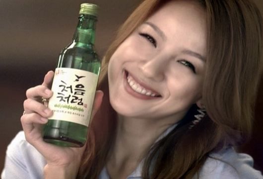 chica coreana sonriendo sosteniendo una botella de soju